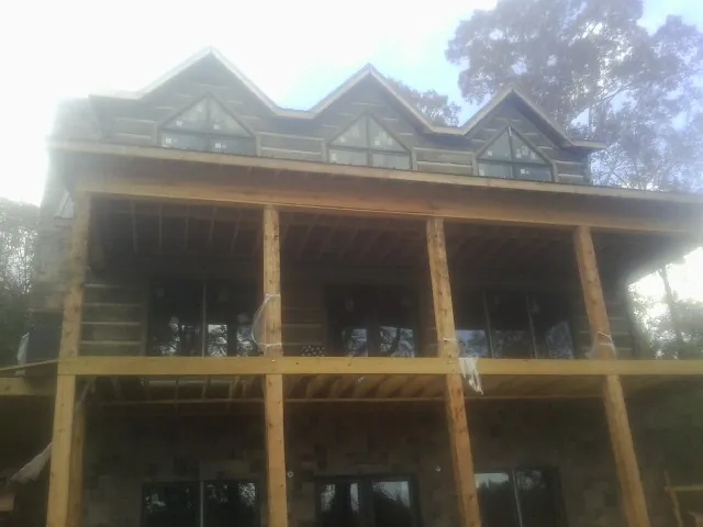 Dormers and porch framing on a large log home under construction — Roof Coating work by our crew in Lincolnton